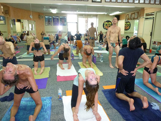 Group of students in Ustrasana (Camel Pose), stretching deeply in Bikram Yoga El Paseo’s studio.