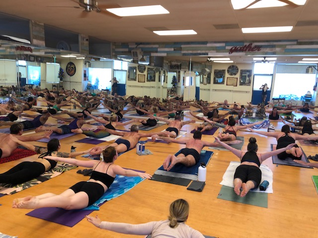 Full Bikram Yoga class in Poorna-Salabhasana (Full Locust Pose) with arms and legs lifted off the mat at Bikram Yoga El Paseo Palm Desert.